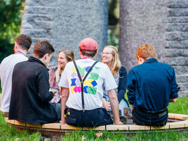 Sechs Personen sitzen im Garten der GLS Bank im Kreis zusammen.