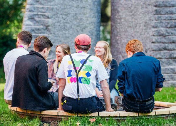 Sechs Personen sitzen im Garten der GLS Bank im Kreis zusammen.